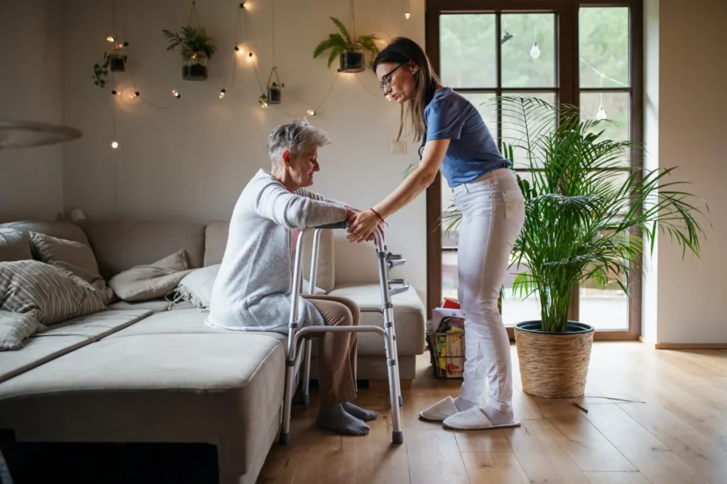 Altenpflegerin hilft einer Seniorin beim Aufstehen